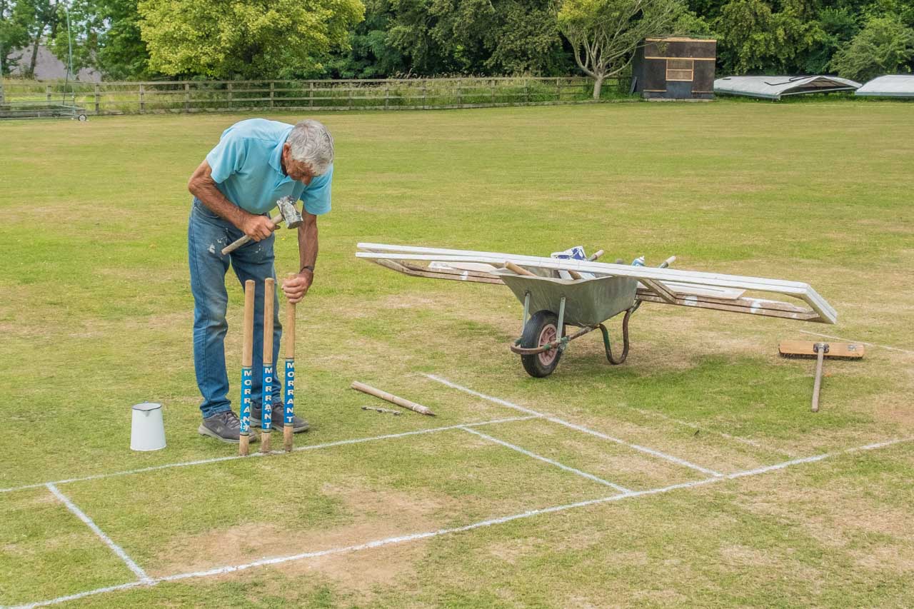 Behind the scenes, John prepares the wicket for the next match